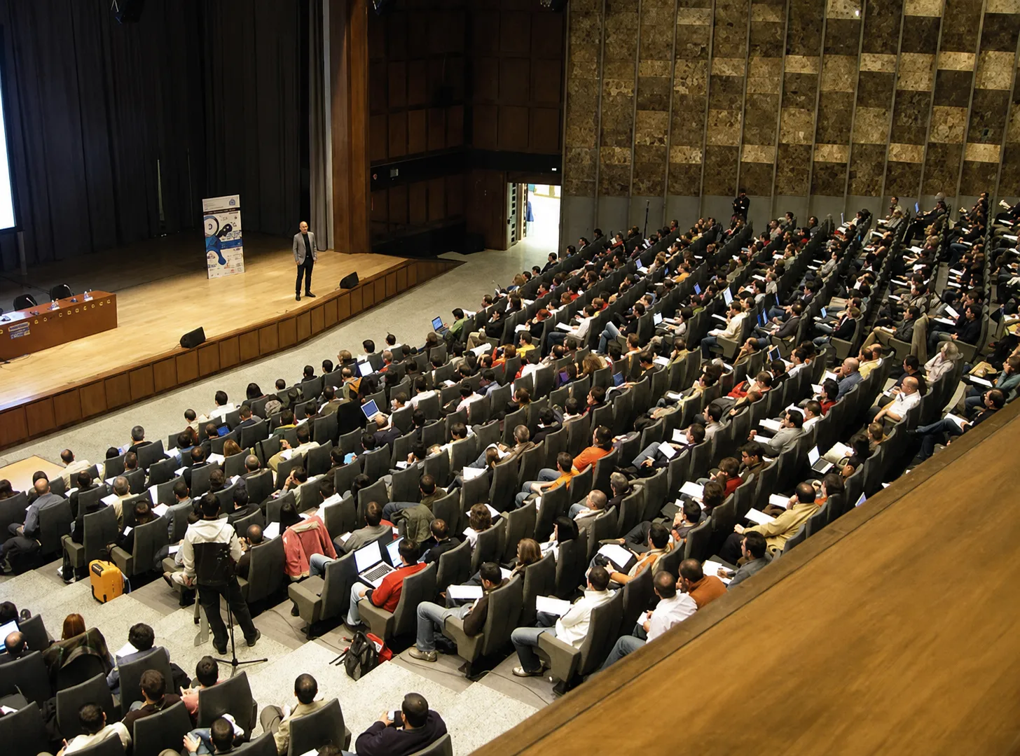 Carlos Castillo speaking to a full auditorium at a financial event